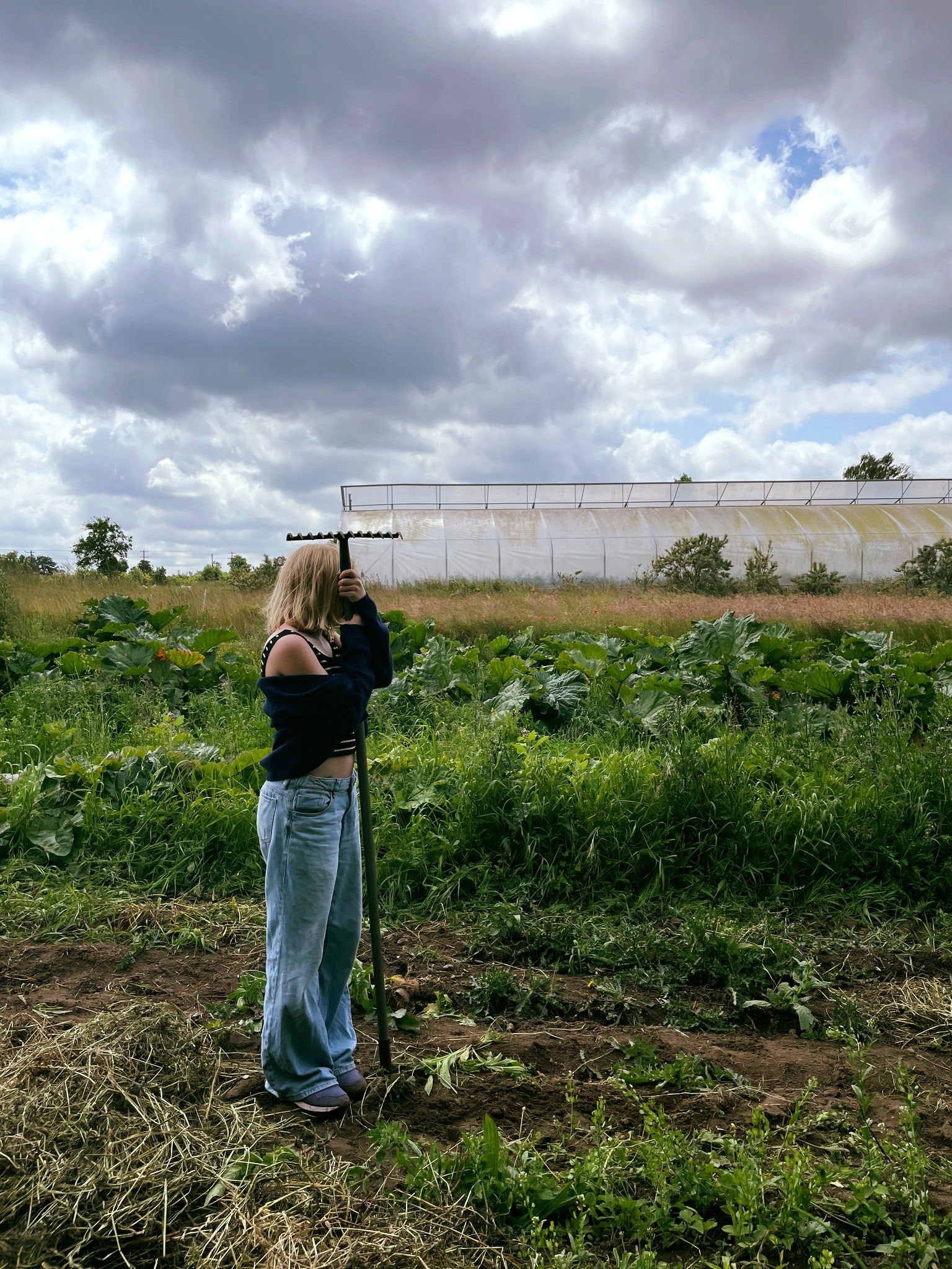 Elev står i marken og hviler op ad en rive og kigger på skyerne. 